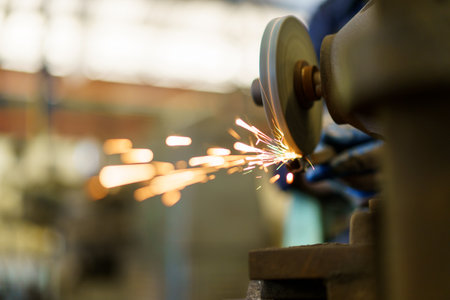 Professional metal work worker sharpening and grinding metal pipe. Man grinds metal profile in factory.の写真素材