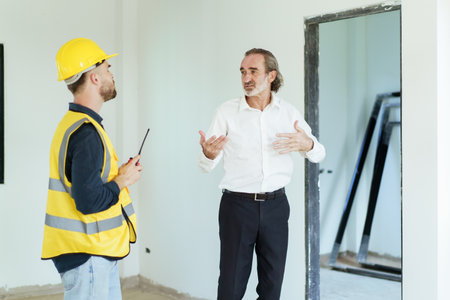 Portrait of caucasian male real estate customer talking - discussing with male building foreman - engineer about construction and interior works. Construction contractor talking with client.の写真素材