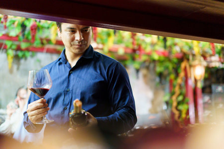 Portrait of good looking caucasian man testing and examining a red wine.