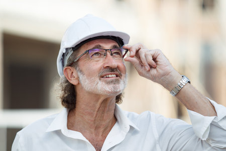 Senior caucasian white civil engineer portrait at construction site. Senior engineer portrait wearing safety hard hat portrait.の写真素材