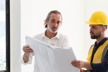 Portrait of caucasian male real estate customer talking - discussing with male building foreman - engineer about construction and interior works. Construction contractor talking with client.の写真素材