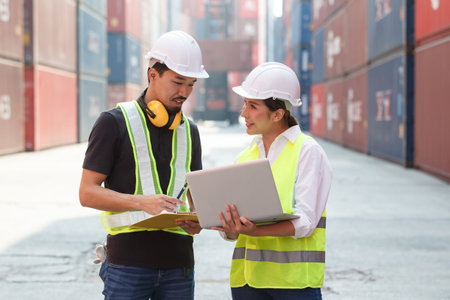 Asian male and female customs officers are currently conducting inspections of containers within the...