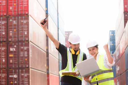 Asian male and female customs officers are currently conducting inspections of containers within the...