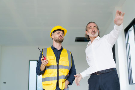 Portrait of caucasian male real estate customer talking - discussing with male building foreman - engineer about construction and interior works. Construction contractor talking with client.の写真素材