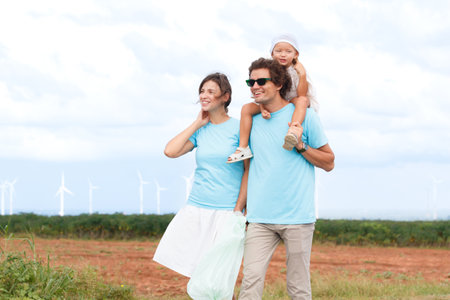 Happy cheerful caucasian white family with daughter are walking and relaxing together in the daytime in nature with windmill towers in background. Happy family activity concept.の写真素材