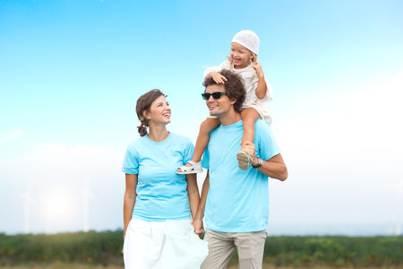 Happy cheerful caucasian white family with daughter are walking and relaxing together in the daytime in nature with windmill towers in background. Happy family activity concept.の写真素材