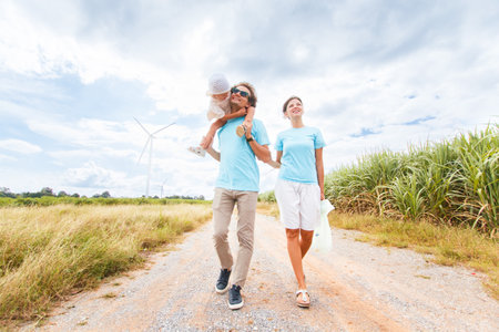 Happy cheerful caucasian white family with daughter are walking and relaxing together in the daytime in nature with windmill towers in background. Happy family activity concept.の写真素材