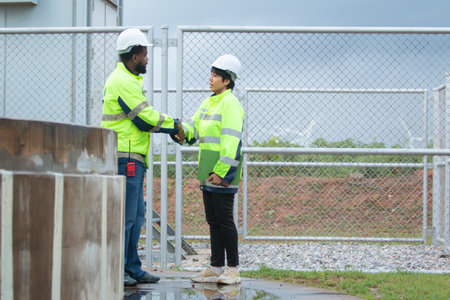Team of electricians engineer are having a conversation and discussion together at electric generator windmill station. Female and male professional engineers are working at electric wind turbine.の写真素材
