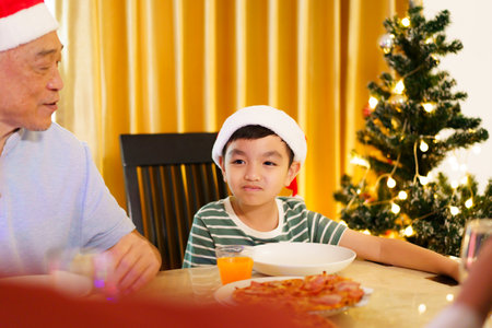 Happy cheerful Asian family is celebrating Christmas and New Year dinner party together, a family with mother, father and son. Asian lovely family celebrate Christmas - New Year festival.の写真素材
