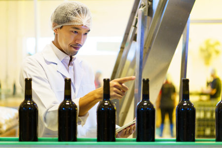 An empty glass bottles are rolling on the alcohol bottling belt machine in the manufacturing...