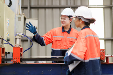 Team of Asian mechanical engineers is having a discussion inside the factory, with the chief...