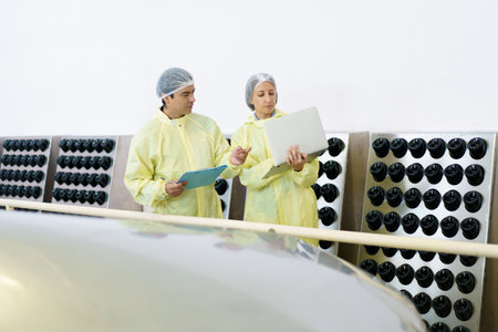 Team of quality control officers or factory engineers are inspecting inside the beverage manufacturing facility. Man and woman engineers working in a food production factory.の写真素材