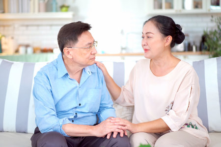 Senior - elderly Asian man is sitting on a sofa in living room with emotional expressions then his...