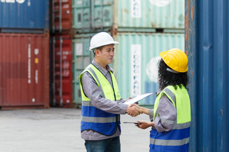 Businesswoman and ship yard engineer are having a discussion about oversea import and export business at container yard. A concept of business and trading across the countries. Global trade concept.の写真素材