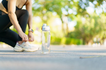 A fit and slim Asian female runner is tie a shoes and prepare herself before starting her running....