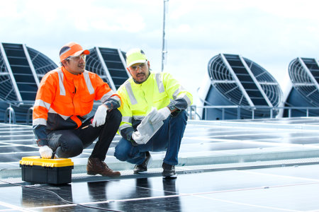 An electrical engineering team installs and wires solar panels on a high-rise rooftop in the city, promoting renewable energy, sustainability, and eco-friendly power solutions for the environment.の写真素材