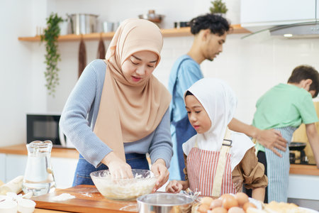 Happy - cheerful Asian muslim man and woman and children are mixing a flour on the kitchen counter...