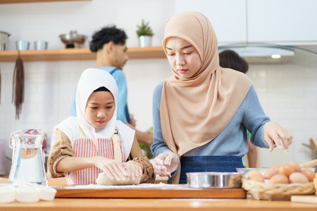 Happy - cheerful Asian muslim man and woman and children are mixing a flour on the kitchen counter...