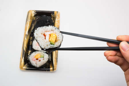 Sushi roll with black chopsticks.の写真素材
