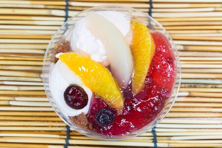 Ice cream and fruits in the plastic bowl on bamboo background.の写真素材