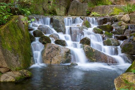Beautiful Waterfalls over a jumble of moss-covered boulders in forest.の写真素材