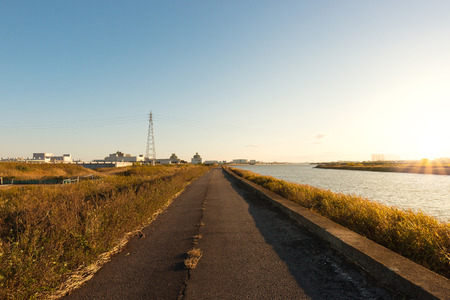 Road along a river at sunset in autumn.の写真素材