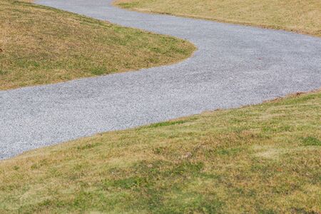 dry grass field with curved walkway road in the park.の写真素材