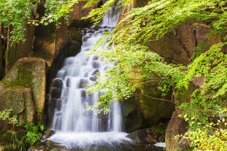 Beautiful Waterfalls over a jumble of moss-covered boulders in forest.の写真素材