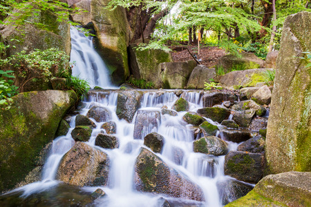 Beautiful Waterfalls over a jumble of moss-covered boulders in forest.の写真素材