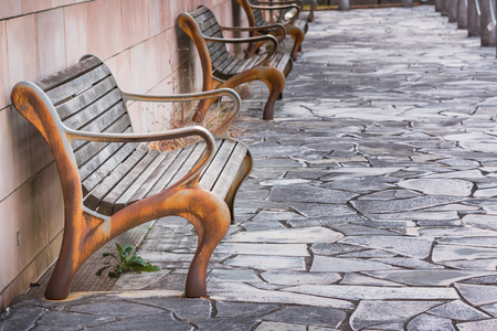 vintage old rusty bench beside red brick wall.の写真素材