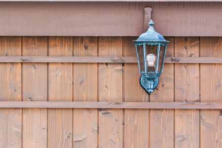 Old fashioned lantern on a brown wooden wall with copy space.の写真素材