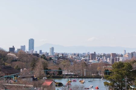 View from park to cityscape with lake and pedal boats in daylight.の写真素材
