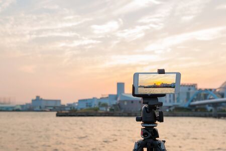 Wonderful sunset over sea harbor, tourist taking a picture by tripod of the seaport
