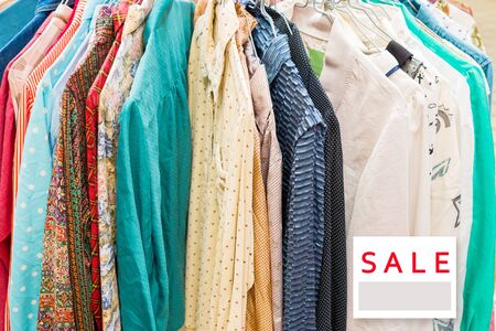 clothes hanging on a rack in a flea market stall. with sale signboard.の写真素材