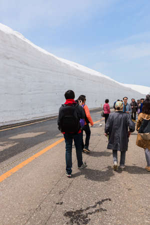 Tateyama, Japan - 2 May 2016: Tourists walk along snow corridor. This snow wall is a part of Kurobe Alpine Route which offers spectacular views around Tateyama mountain.のeditorial素材