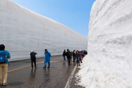 Tateyama, Japan - 2 May 2016: Tourists walk along snow corridor. This snow wall is a part of Kurobe Alpine Route which offers spectacular views around Tateyama mountain.のeditorial素材