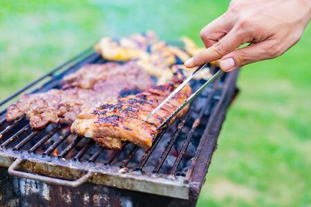 Cooking BBQ meat at festival outdoor in park. Concept of summer party with families and friends.の写真素材