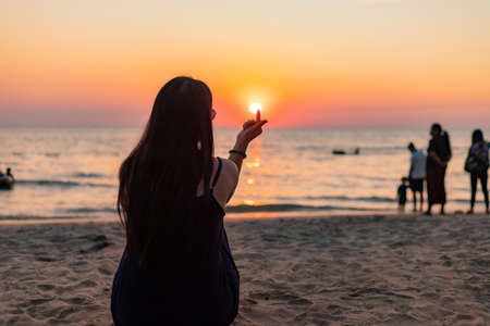 Silhouette at sunset. Female on beach against the sky pass sunbeamの写真素材