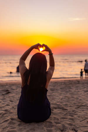 Silhouette Hands in shape of love heart at sunset. Female hands of heart against the sky pass sun beams, concept happy in loveの写真素材