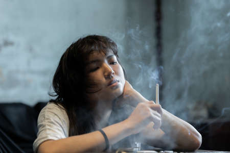 Asian girl smoking and hopeless concept, feeling be absent-minded, Lonely girl conceptの写真素材
