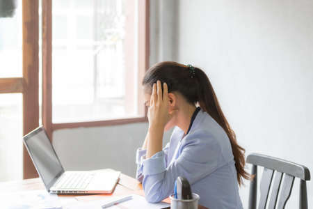 Asia business women feeling headache and stress. She is working at the office desk in front of...
