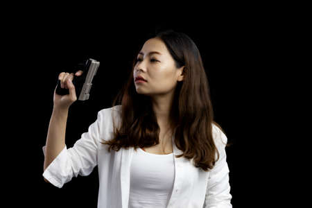 Portrait asian woman wearing a white suit one hand holding a pistol gun on black background