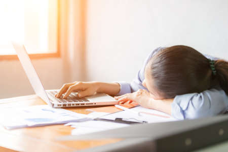 Asia business women feeling sleepy after long time working at the office desk in front of laptop....