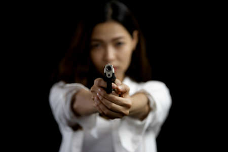 Portrait asian woman wearing a white suit one hand aiming a pistol gun on black backgroundの写真素材