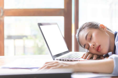 Asia business women feeling sleepy after long time working at the office desk in front of laptop. Business and finance concept.の写真素材