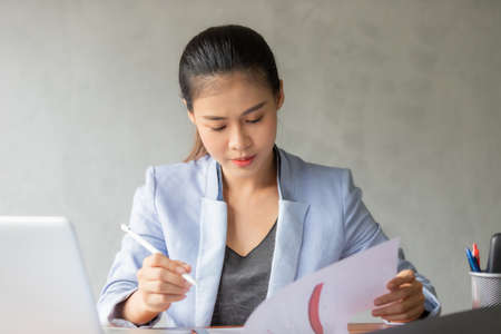 Business asian woman working at home and see information from laptop. Business, finance and technology concept.の写真素材