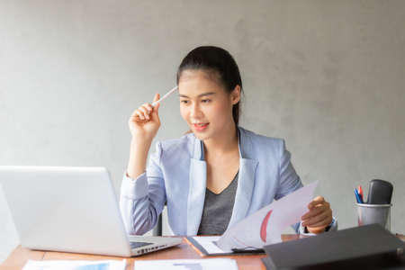 Business asian woman working at home and see information from laptop. Business, finance and technology concept.の写真素材