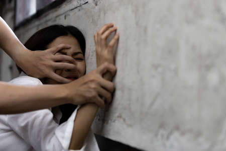 Sexual abuse with a man attacking to a scared woman in a dark placeの写真素材