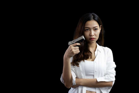 Portrait asian woman wearing a white suit one hand holding a pistol gun on black backgroundの写真素材