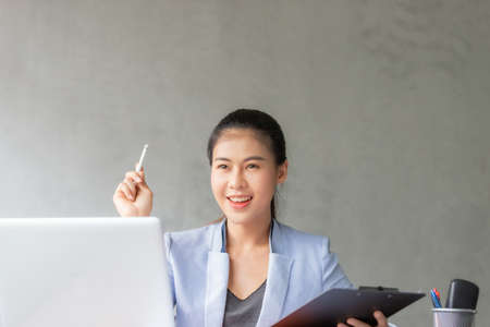 Business asian woman working at home and see information from laptop. Business, finance and technology concept.の写真素材